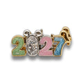 A gold-plated 2027 charm featuring colorful glittery numbers '2', '0', '2', and '7' with a central oval clear gemstone, displayed on a reflective white surface.
