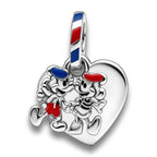 A silver heart-shaped charm featuring two cartoon characters holding red and blue hearts, with a striped bail at the top in red, white, and blue, shown on a white background with a soft reflection.