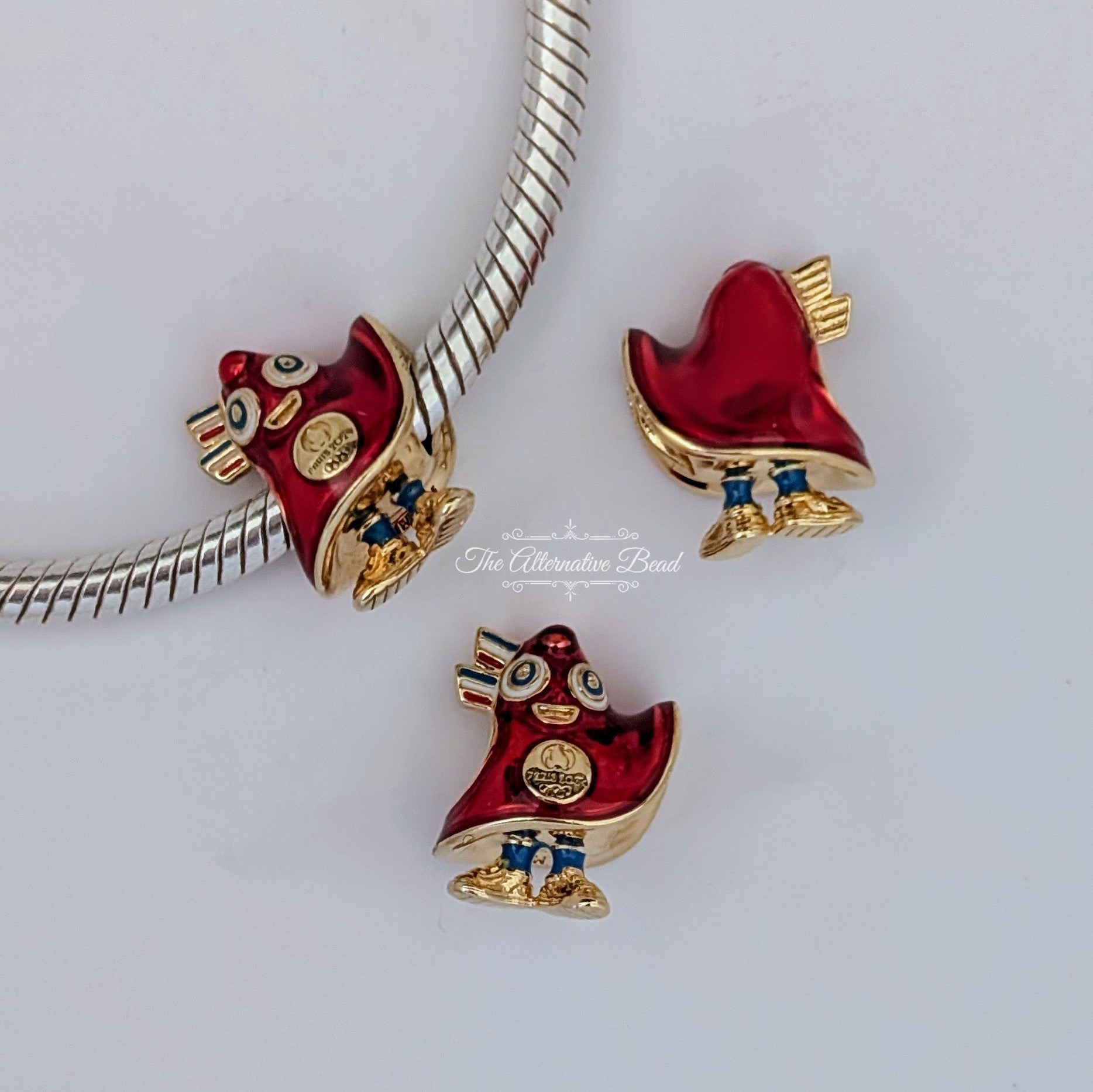 Pandora Paris 2024 Olympic Games Mascot Charm (763465C01) gold and red and blue gold and enamel Bead by The Alternative Bead. Your Jewelry Retailer from Germany