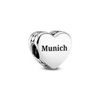 Heart-shaped silver charm with 'Munich' engraving on a white background