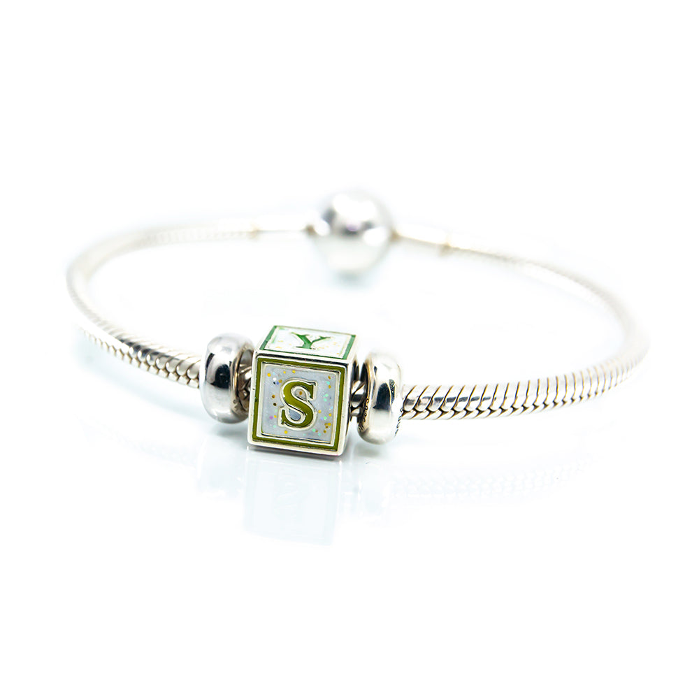 Silver bracelet with a green and white square charm featuring the letter 'S' on a white background