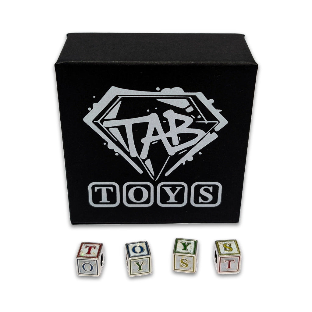 Black box with 'TAB TOYS' logo and lettered toy blocks on a white background